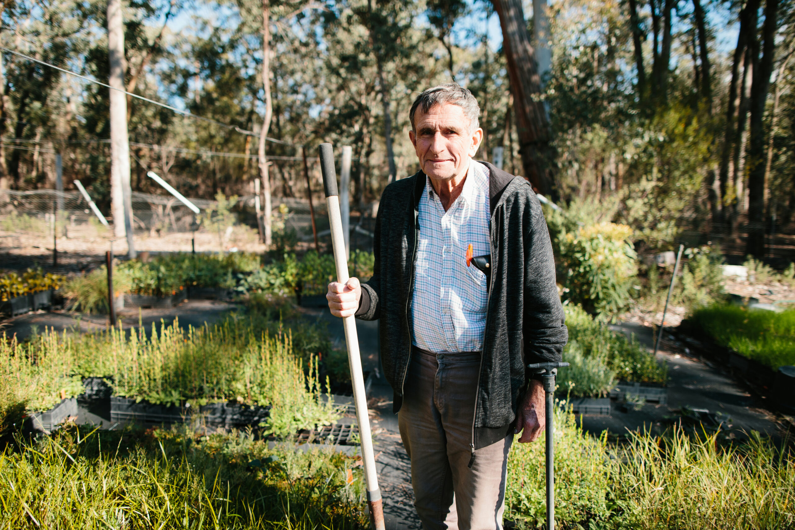 John Topp leaning on a shovel in his nursery at Valencia Creek